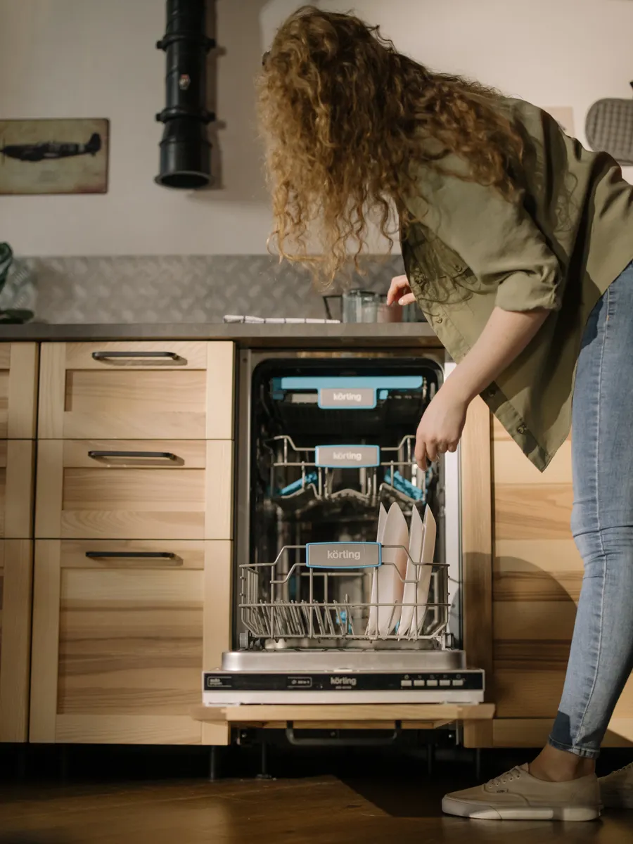 A person checking household dishwasher parts to adjust their maintenance routine.