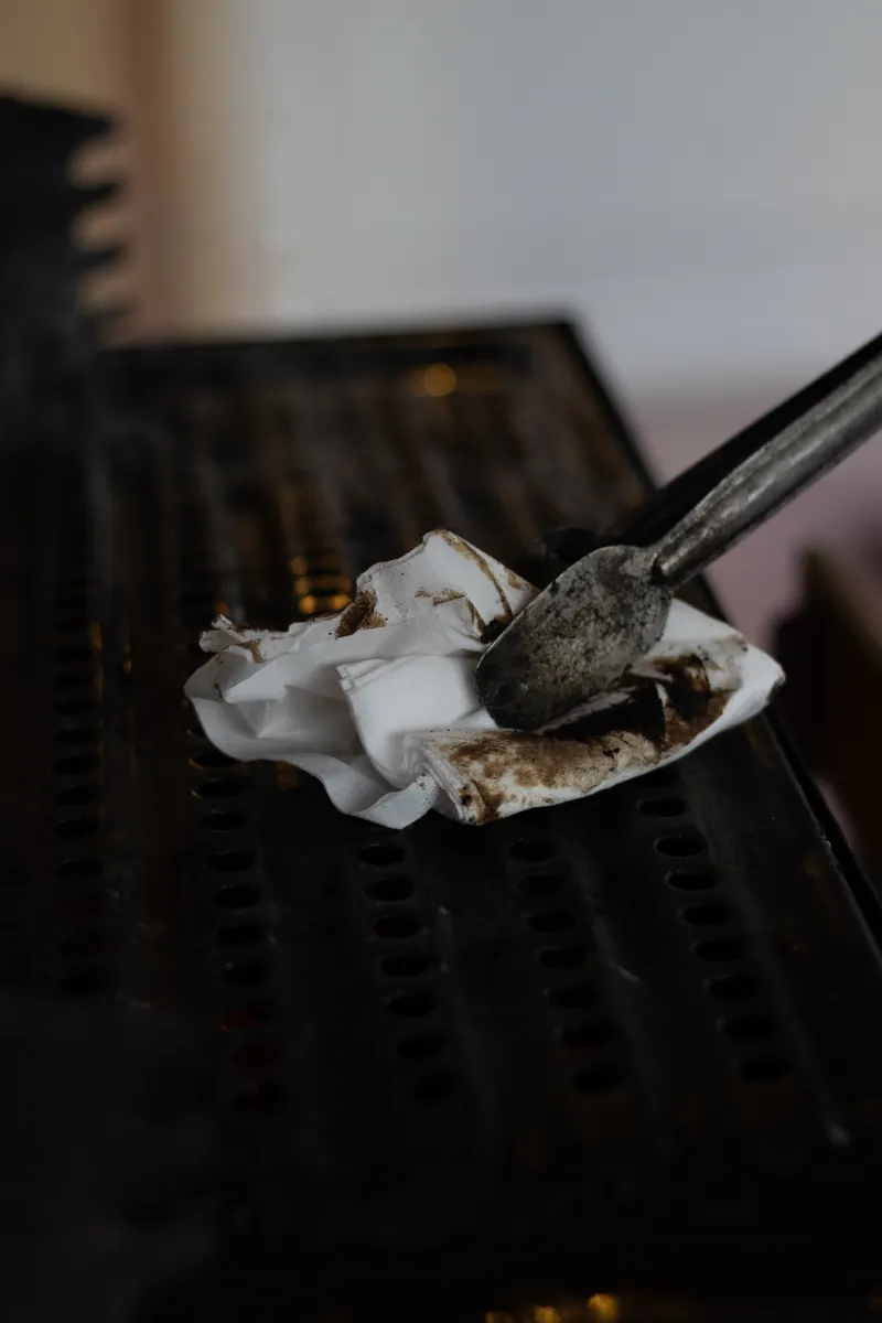 Applying baking soda paste to stubborn grease and food residue on stove surfaces.