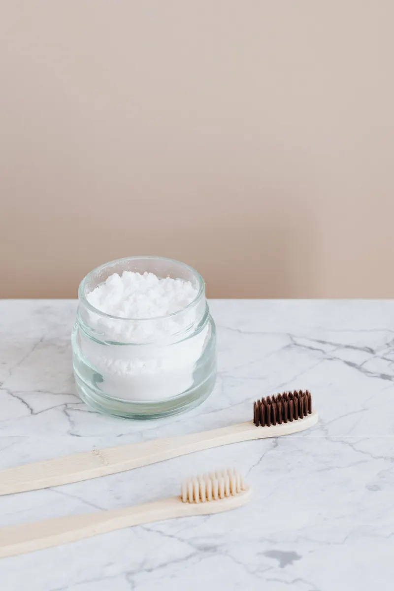 Glass bowls filled with baking soda and white vinegar, commonly used for deep kitchen cleaning.