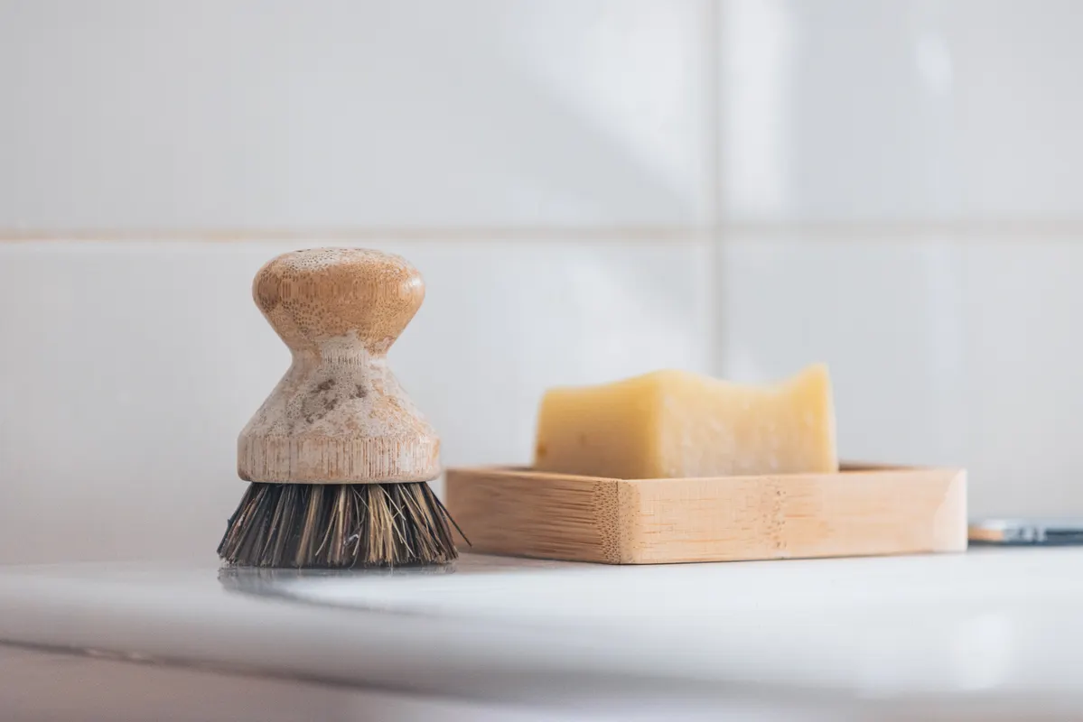 Using a soft brush to clean grease and grime around kitchen cabinet handles and knobs.