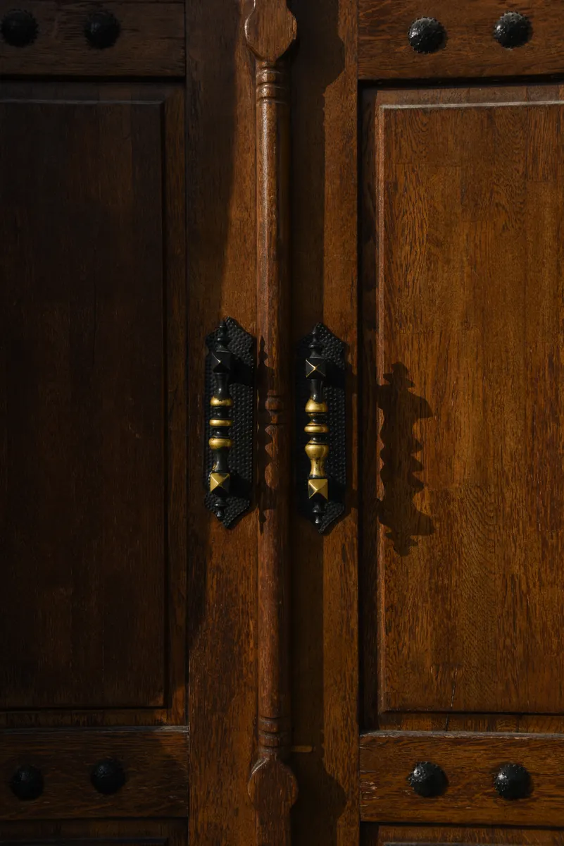 Close up of a soft brush cleaning around cabinet hinges and metal knobs.
