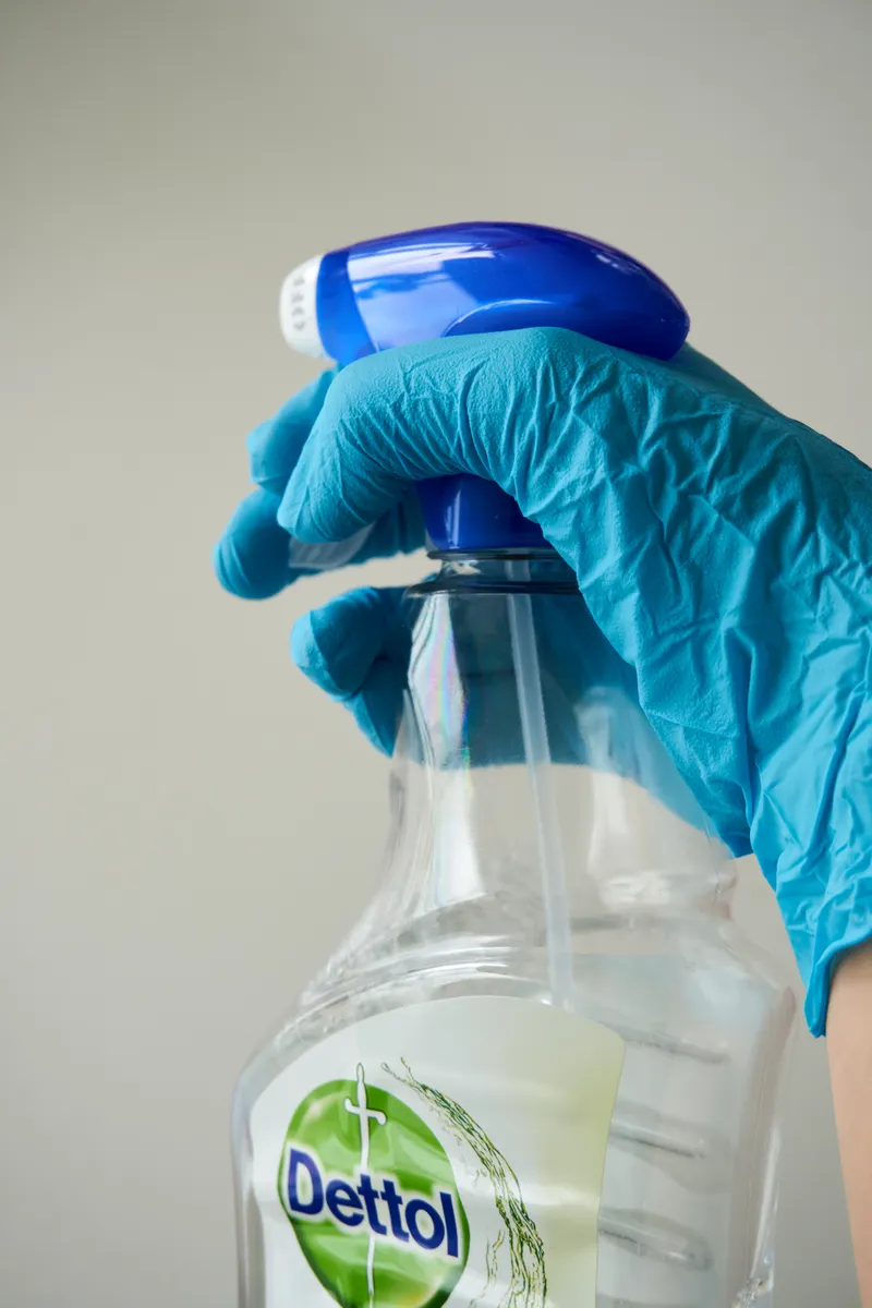 Measuring cleaning product dilution ratios with a chart and spray bottle for safe household surface cleaning.