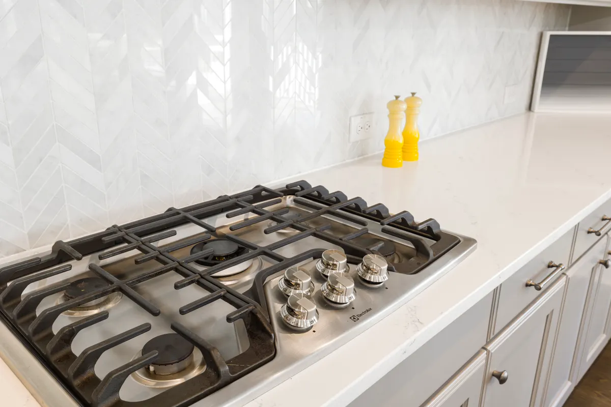Checking a commercial degreaser label before cleaning near the oven stovetop edge.