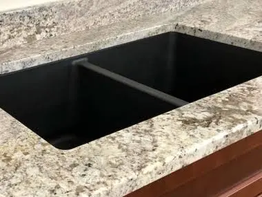 Durable composite granite kitchen sink wiped dry to prevent mineral deposits and water spots.