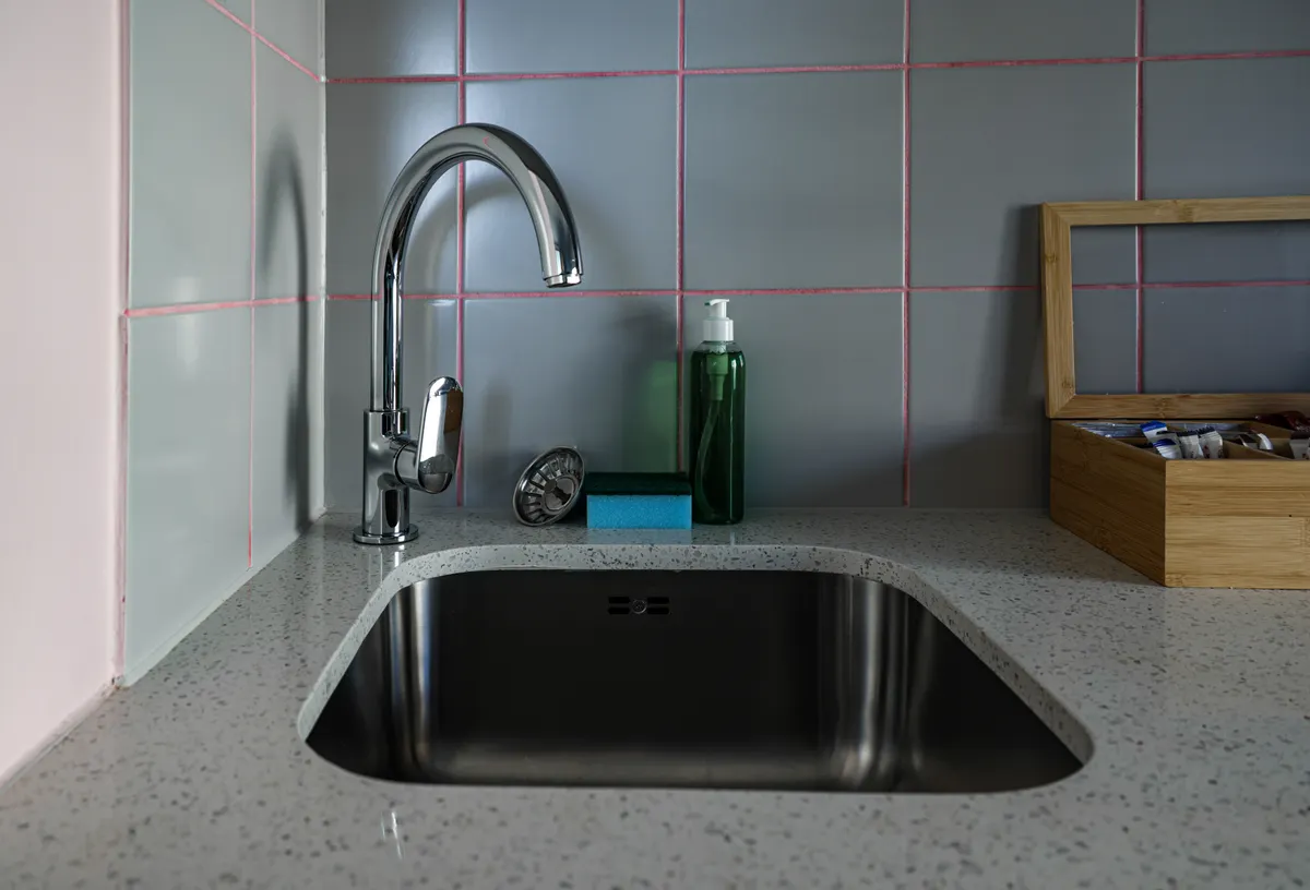 Treating persistent surface discoloration on a dark granite composite kitchen basin.