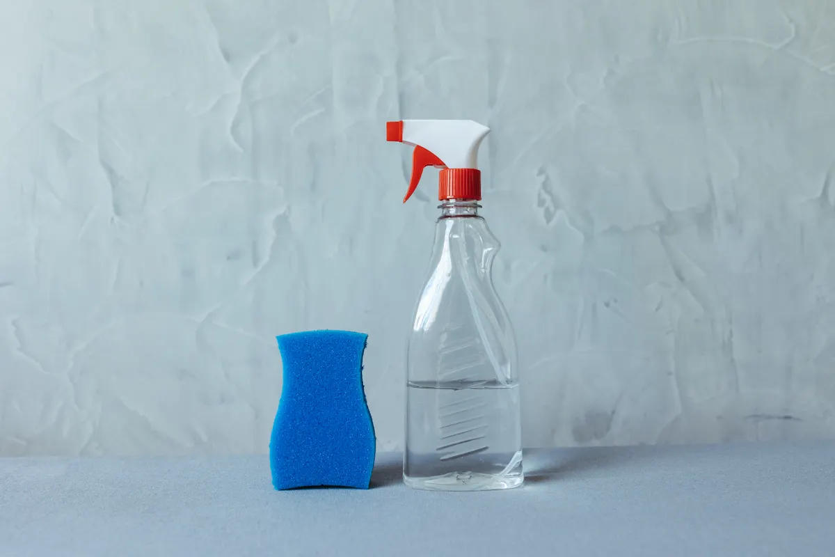 A bottle of specialized cooktop cleaner standing beside a glass stovetop.
