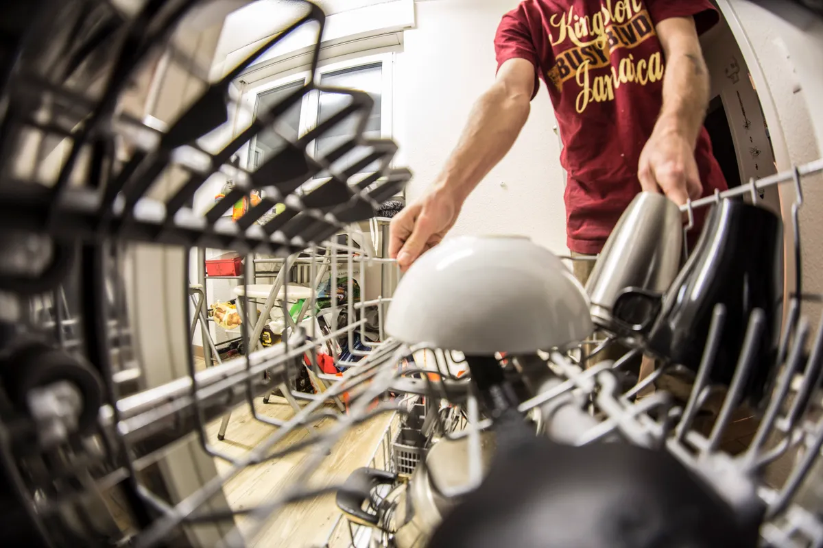 Checking and hand spinning a clean dishwasher spray arm before reinstalling it inside the appliance.