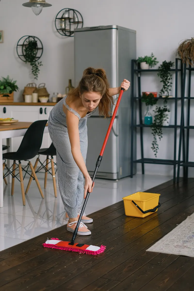 A dry dust mop removing loose debris and grit before wet mopping the kitchen floor.