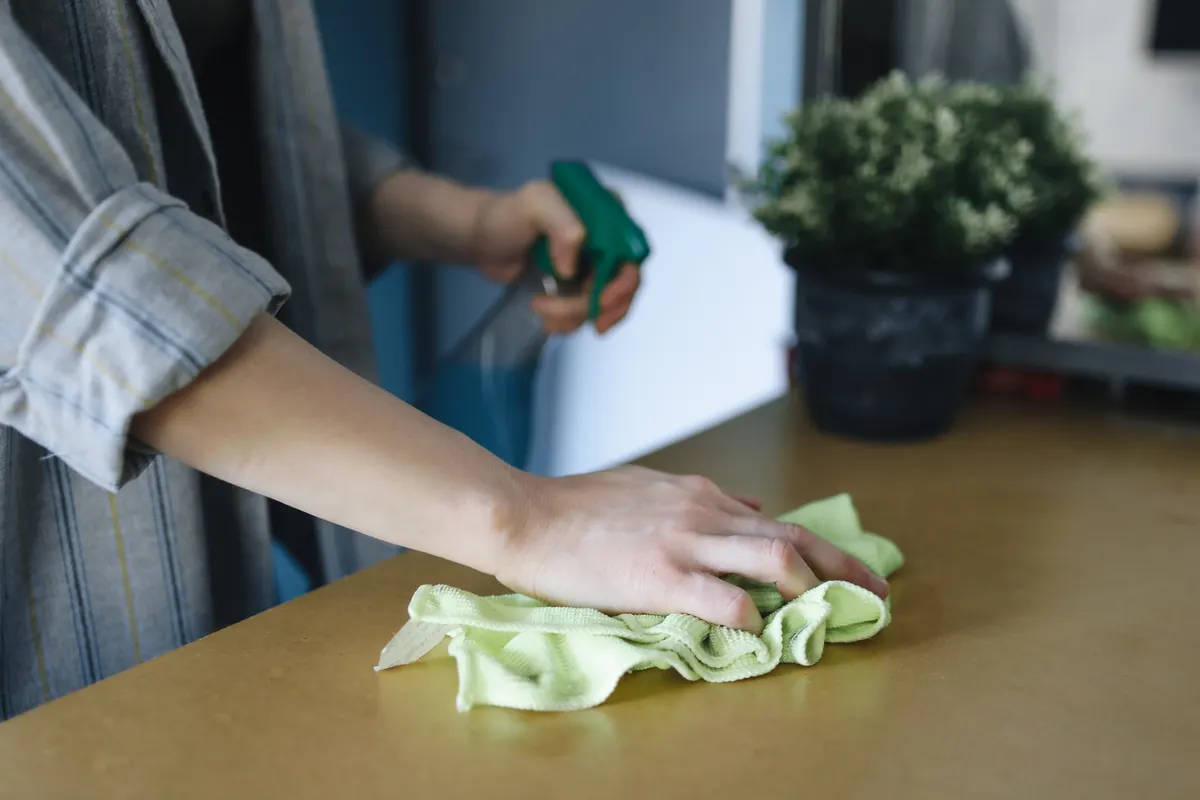 Natural cleaning products and microfiber cloths on a kitchen counter.