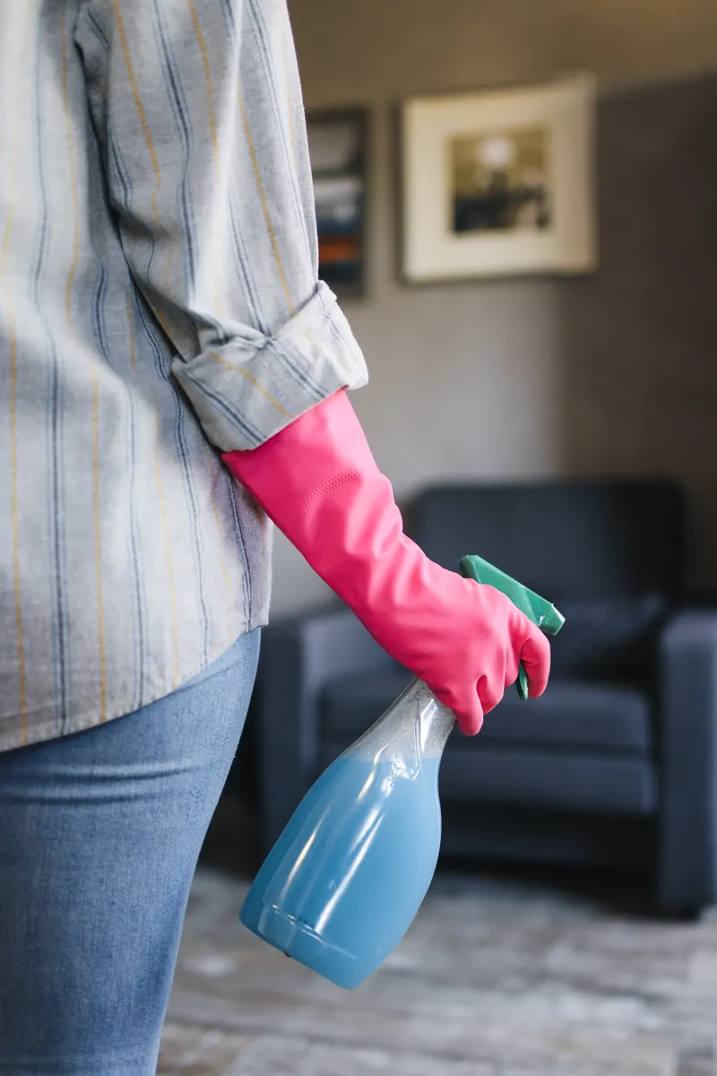 A hand holding a spray bottle with a mild cleaner, demonstrating careful kitchen cleaning.