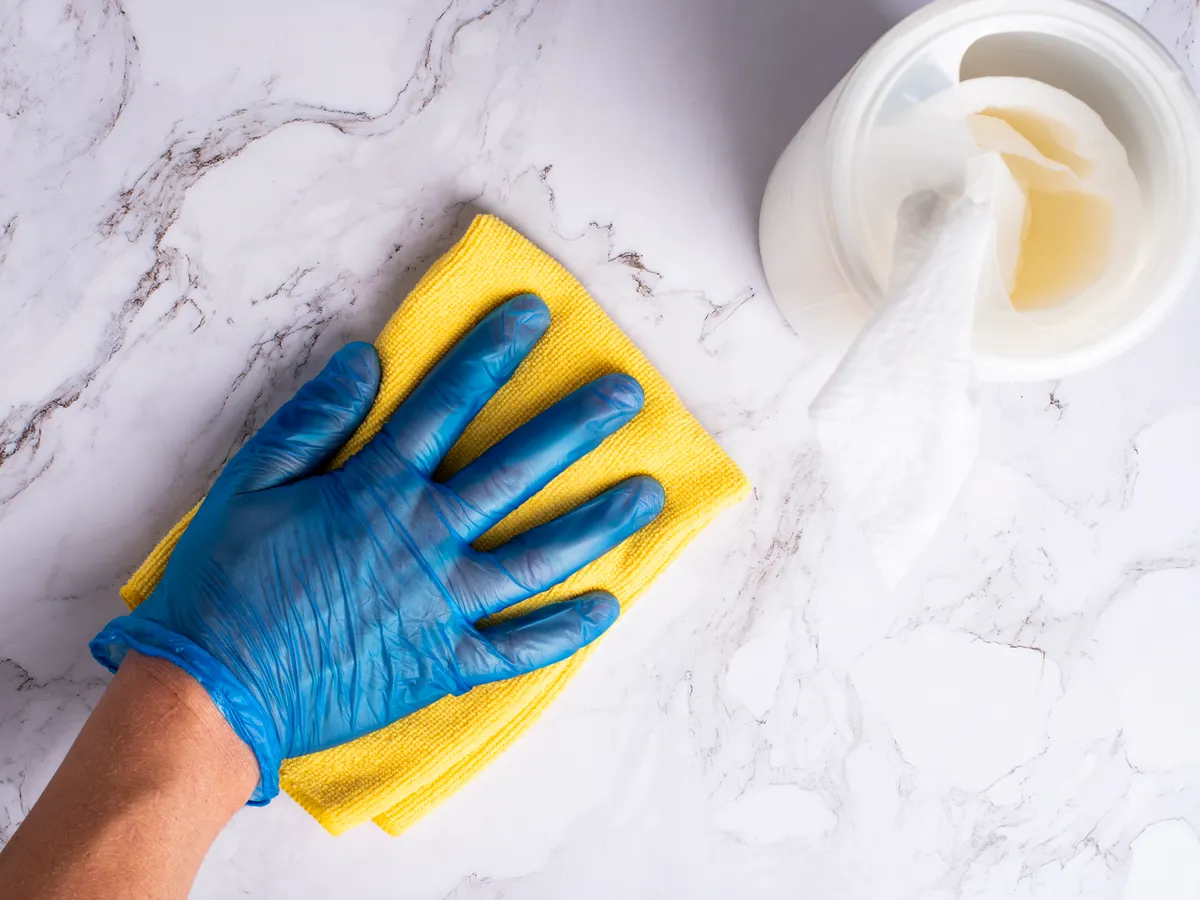 Wiping down a kitchen countertop finish safely with warm water and mild soap.