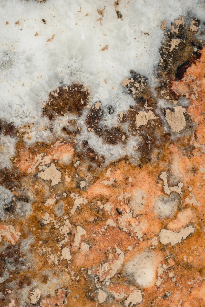 A granite countertop surface near a kitchen sink showing hard water spots and mineral buildup.