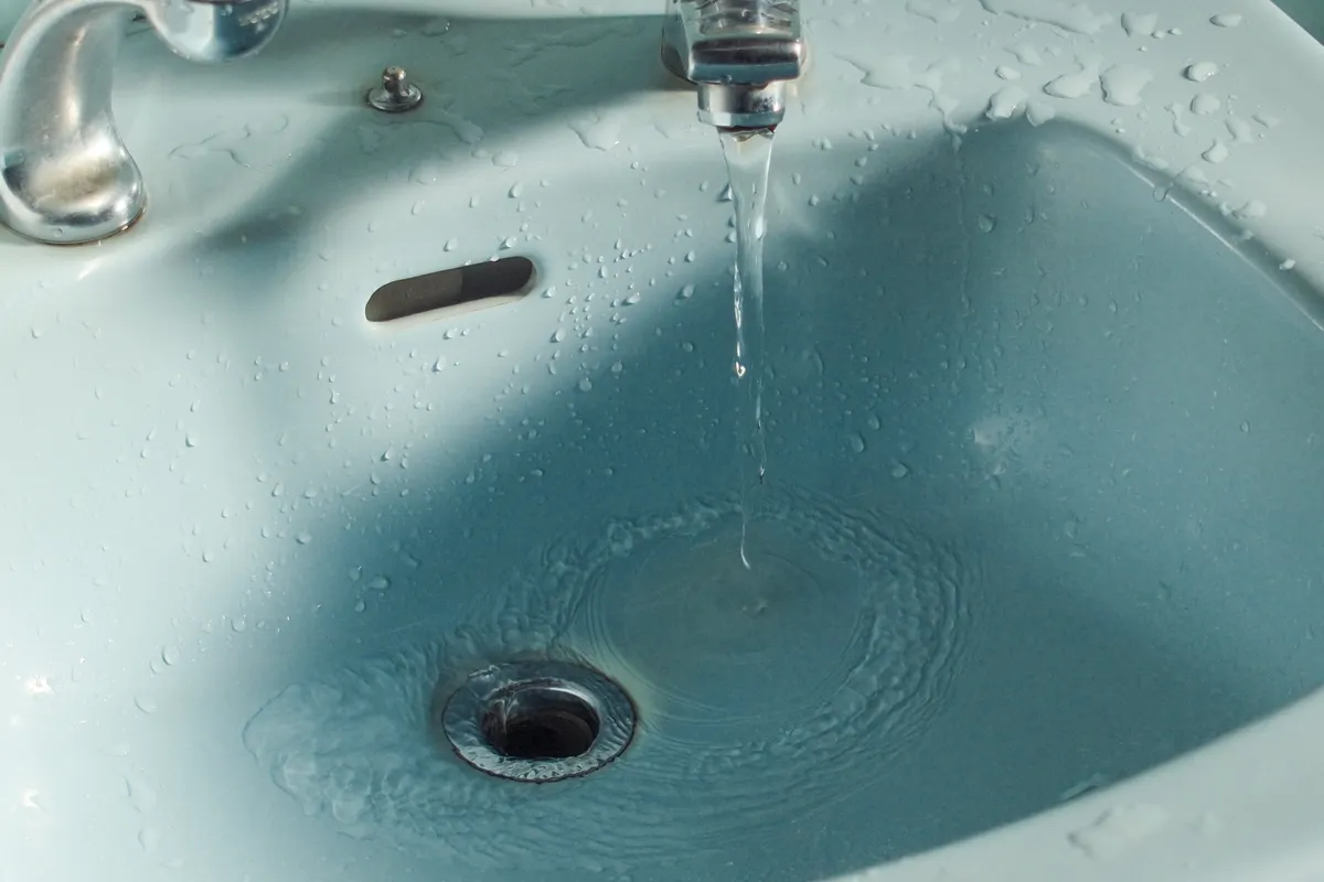 Hot water running from the kitchen faucet to flush grease out of the sink drain.