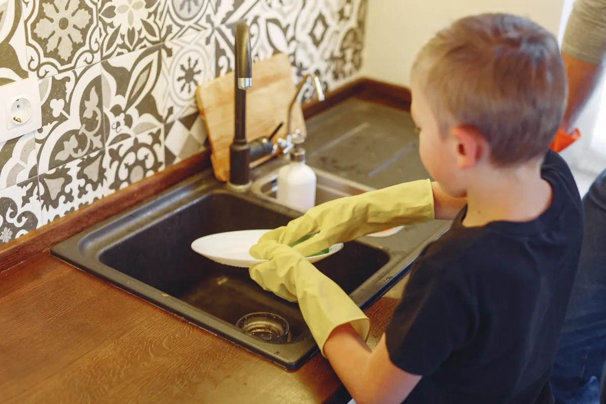 Child helping with simple kitchen chores like wiping counters.