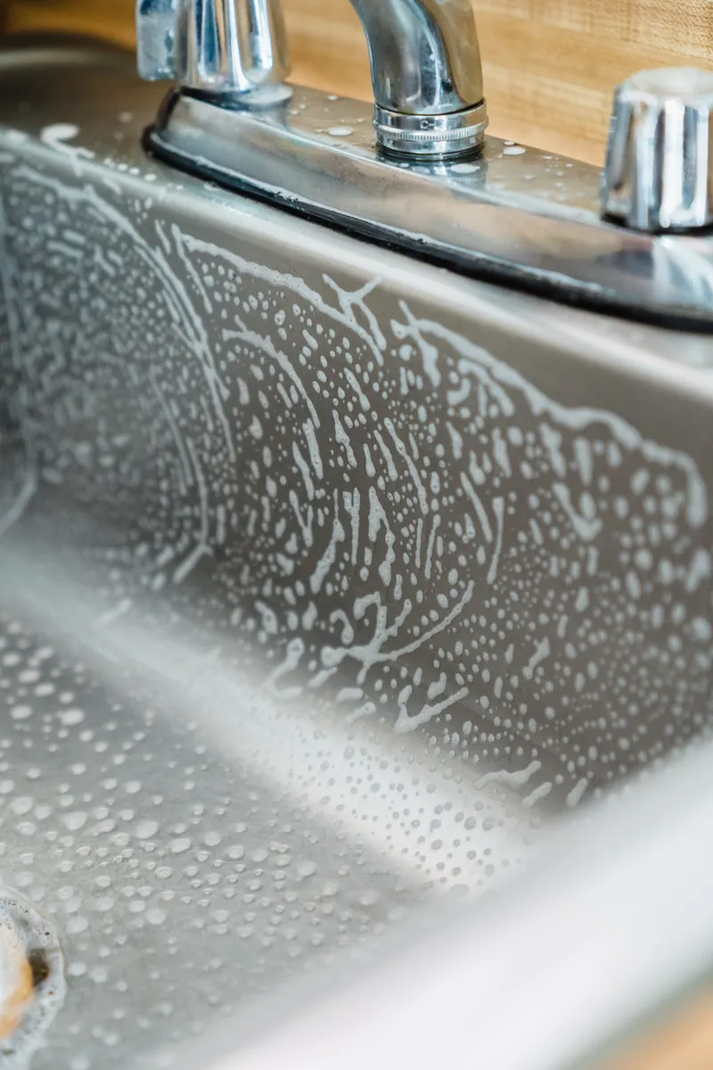 A close-up view of a clean kitchen counter surface and stainless steel sink area during troubleshooting.