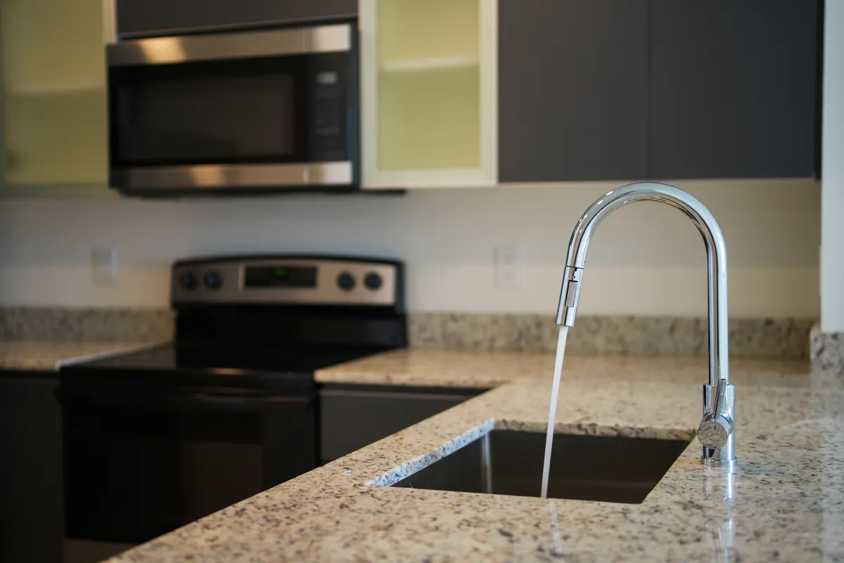 Close-up of a kitchen faucet spout and handle showing finish details.
