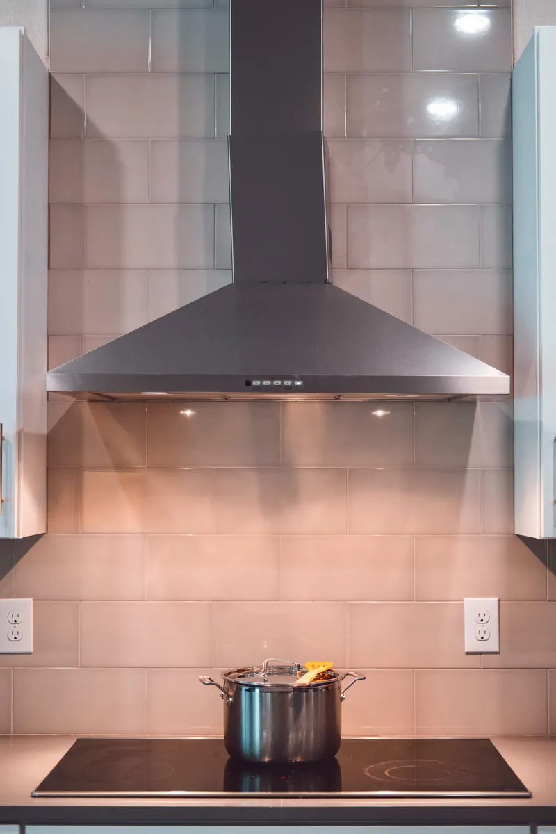 A stainless steel range hood and vent filter installed above a kitchen stove.