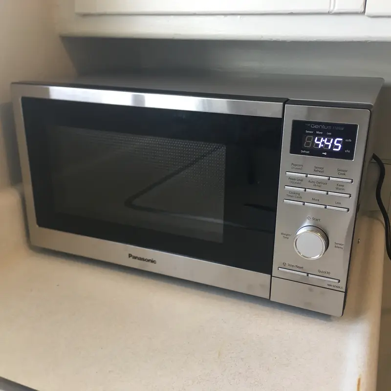 Carefully wiping the exterior keypad and digital display of a microwave.