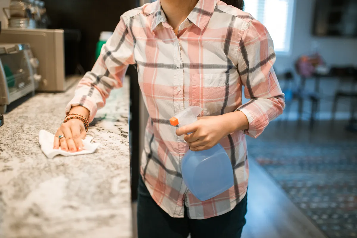 A spray bottle and cloth on a kitchen counter for natural cleaning and disinfecting.