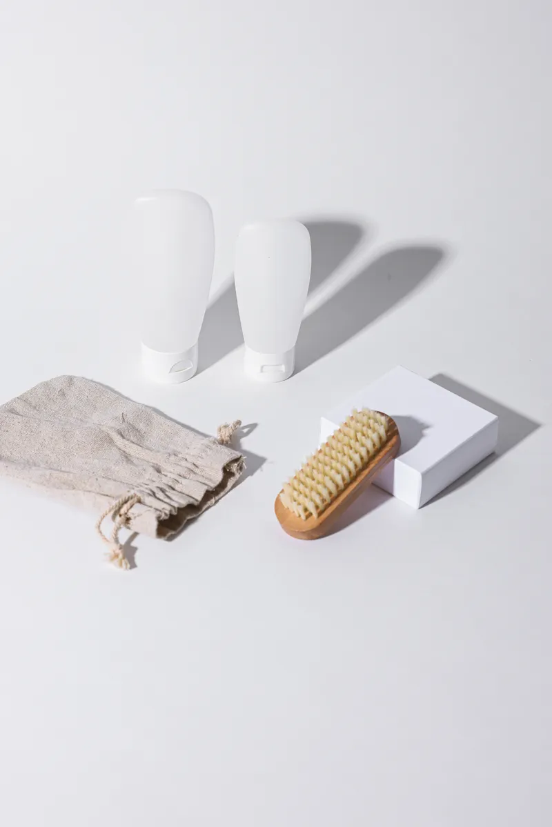 A soft-bristled brush and microfiber cloths displayed next to bottles of natural cleaning solutions.