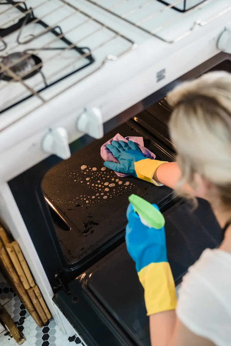 Applying a gentle baking soda paste carefully to protect the textured oven interior coating.