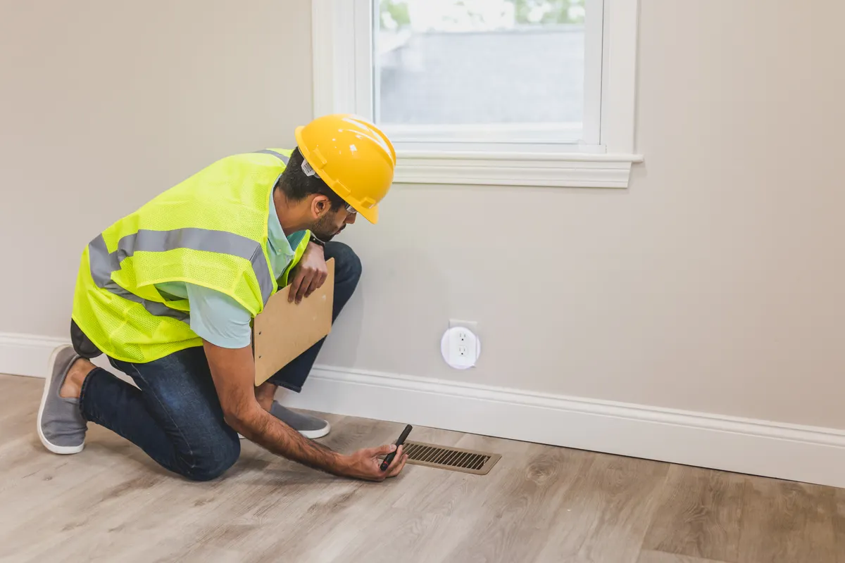 A homeowner carefully inspecting delicate hardwood flooring before testing an unfamiliar cleaning product.