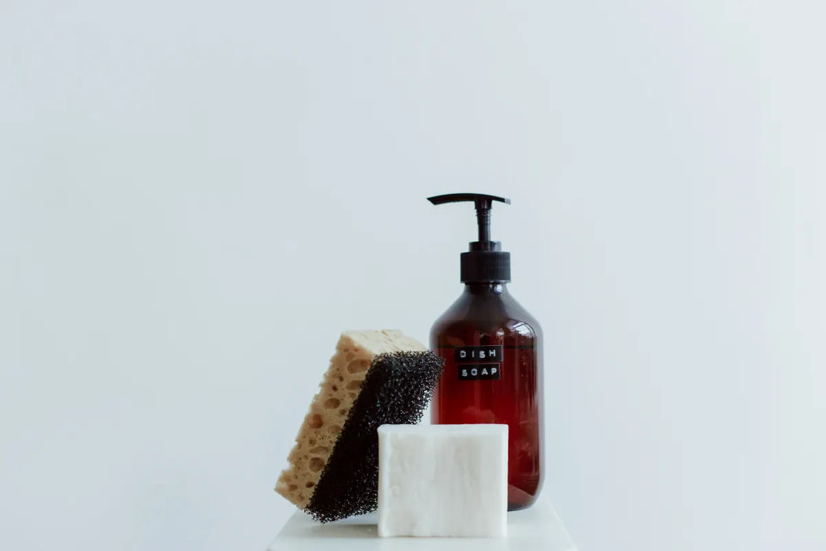 A bottle of dish soap and a jug of white vinegar for cleaning appliances.