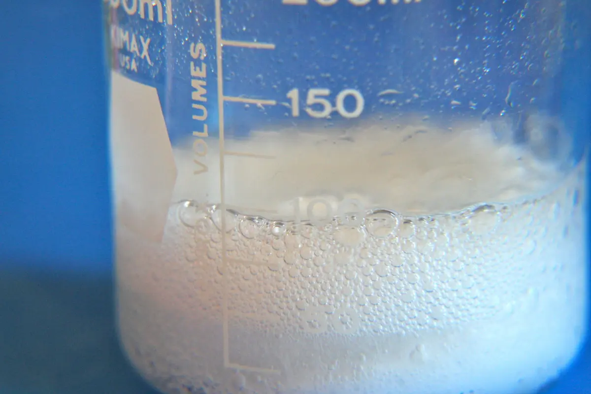 Safe natural cleaning supplies like baking soda and white vinegar sitting next to a ceramic sink.