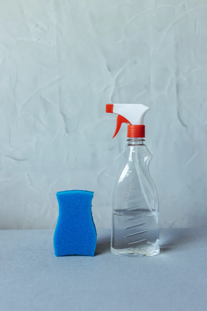 A spray bottle of commercial cleaner resting near a kitchen counter during routine cleaning.