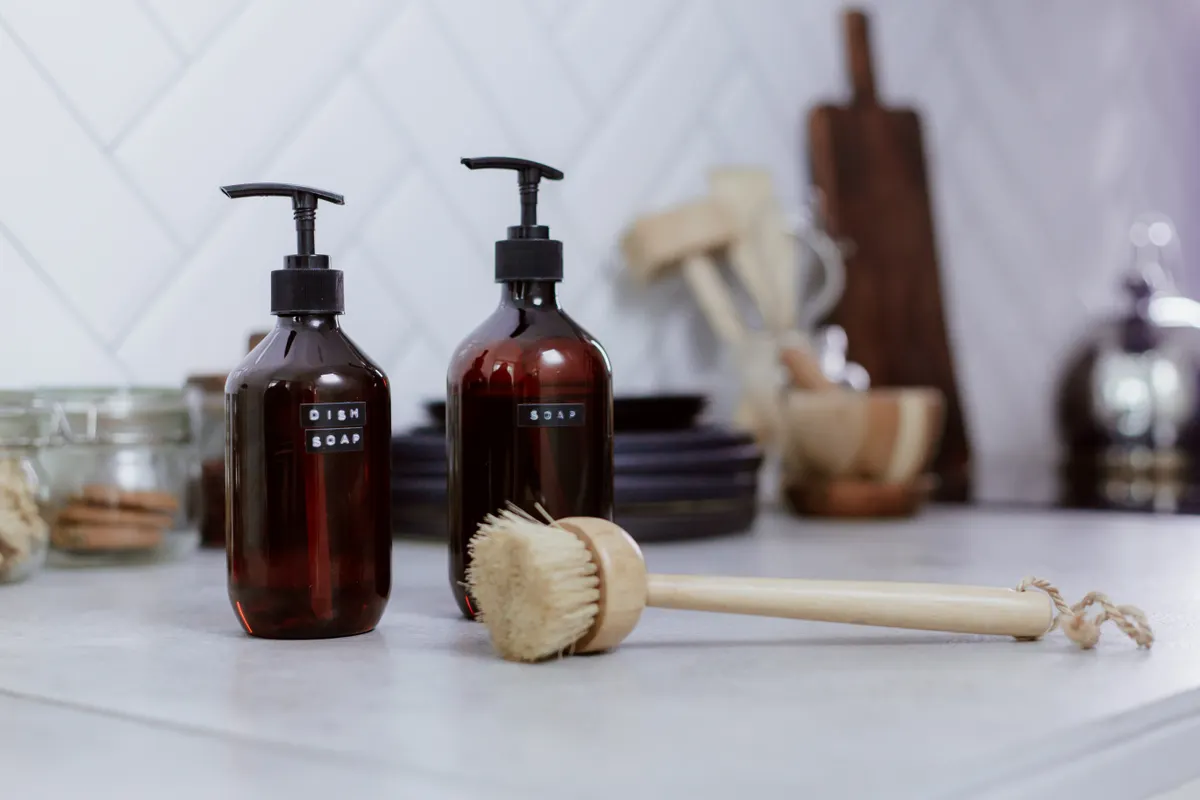 Bottles of safe cleaning products and soft cloths arranged on a kitchen counter.