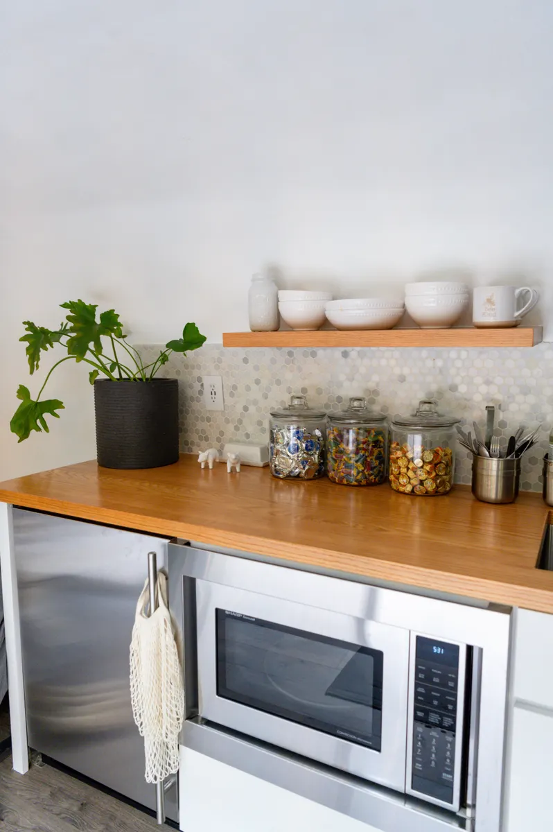 Natural kitchen cleaning supplies including baking soda and white vinegar next to a microwave.