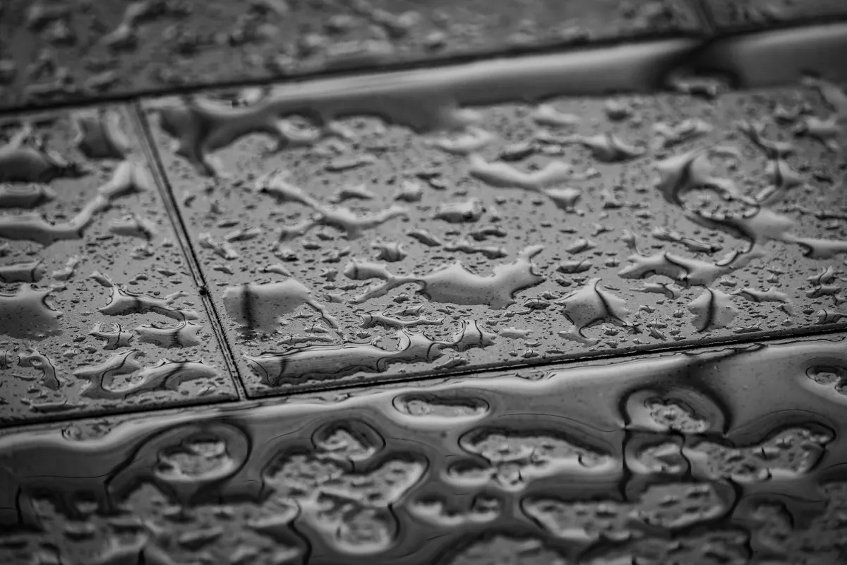 A sealed natural stone kitchen floor resisting water droplets during a routine material test.