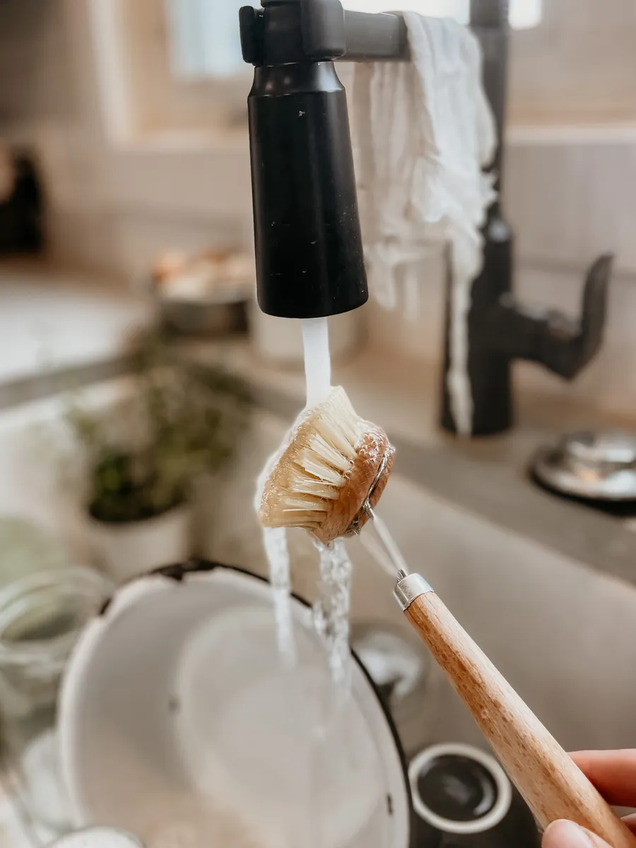Kitchen cabinet pulls soaking in a bowl of warm soapy water for deeper cleaning.
