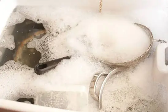 Oven racks soaking in a bathtub with warm soapy water for carbon buildup.
