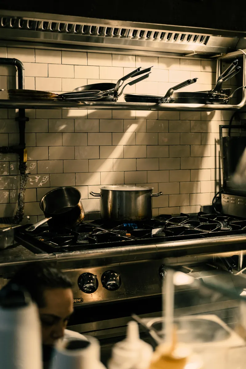 Grease settled in gaps and filters around a kitchen stove causing a lingering smell.