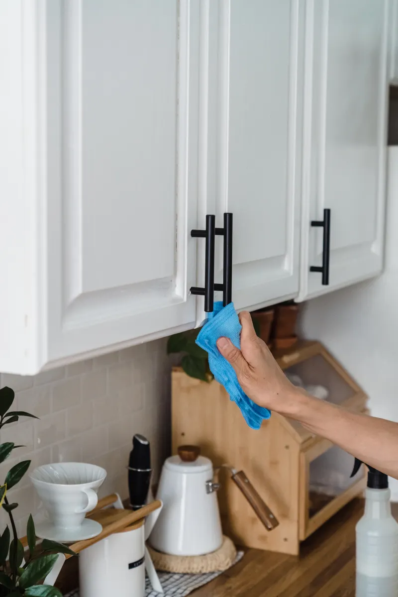 Hand spraying a small, inconspicuous area of a cabinet interior to test a cleaning product.