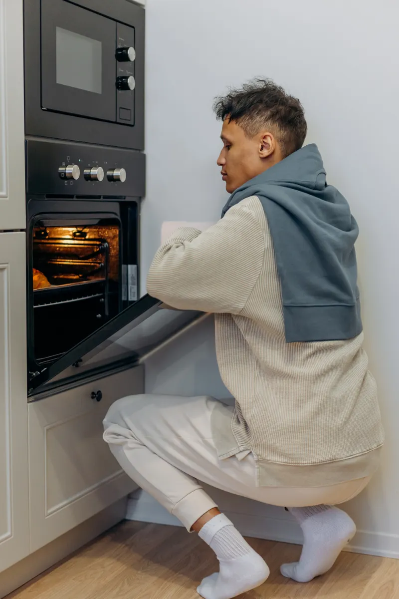 Wiping down an oven exterior thoroughly to remove grease after heavy cooking.