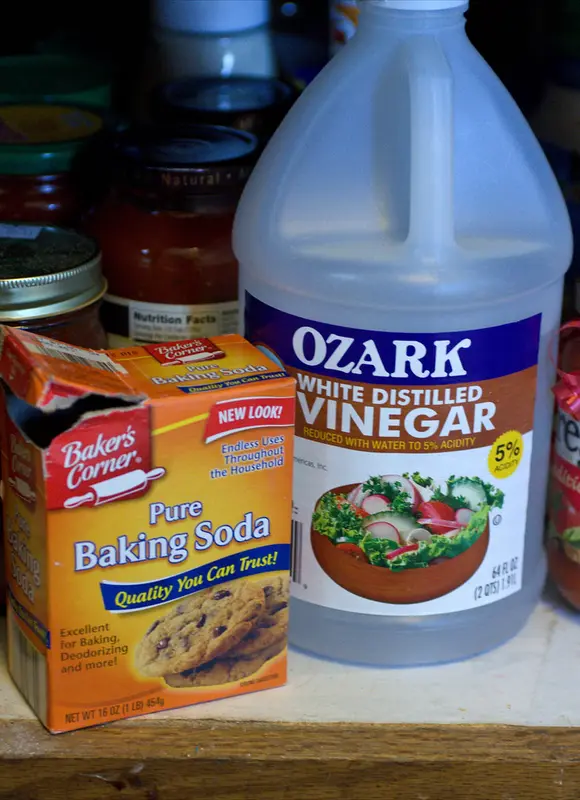 Bottles of vinegar and baking soda placed together as a gentler everyday kitchen cleaner alternative.