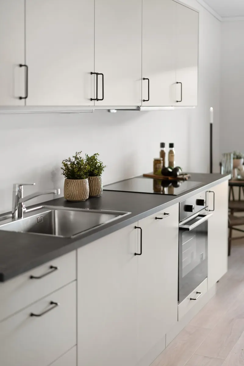 A spray bottle and cloth resting on a clean kitchen countertop near cabinet fronts.